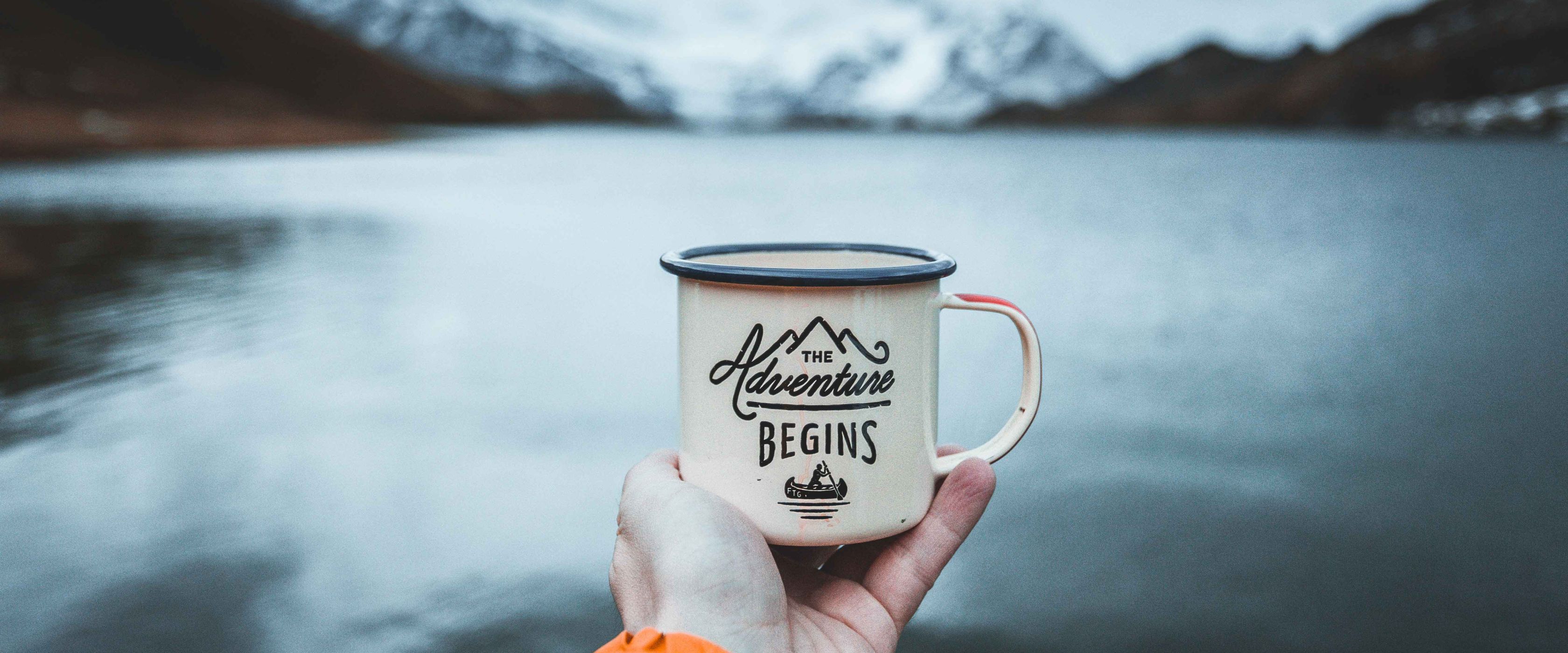 Someone holding mug in front of a lake