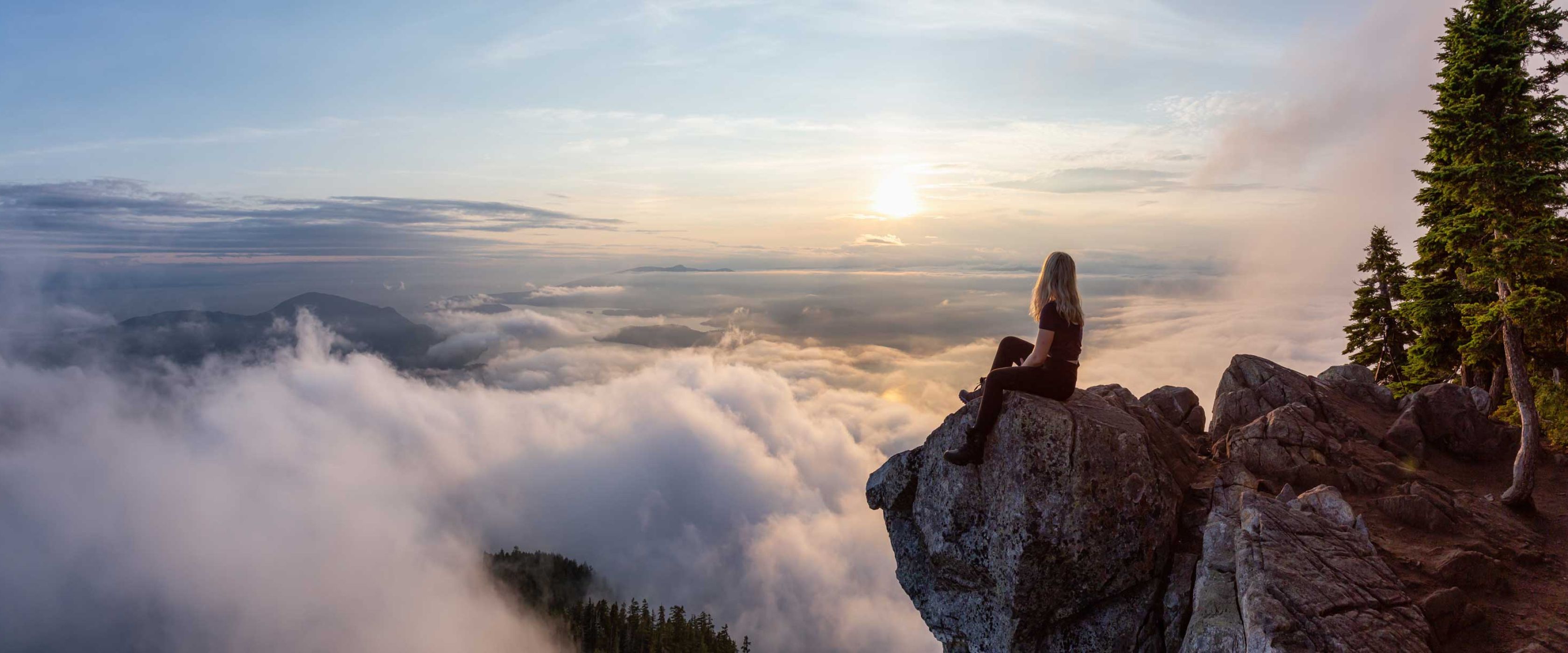 Women sitting on a cliff overlooking a valley