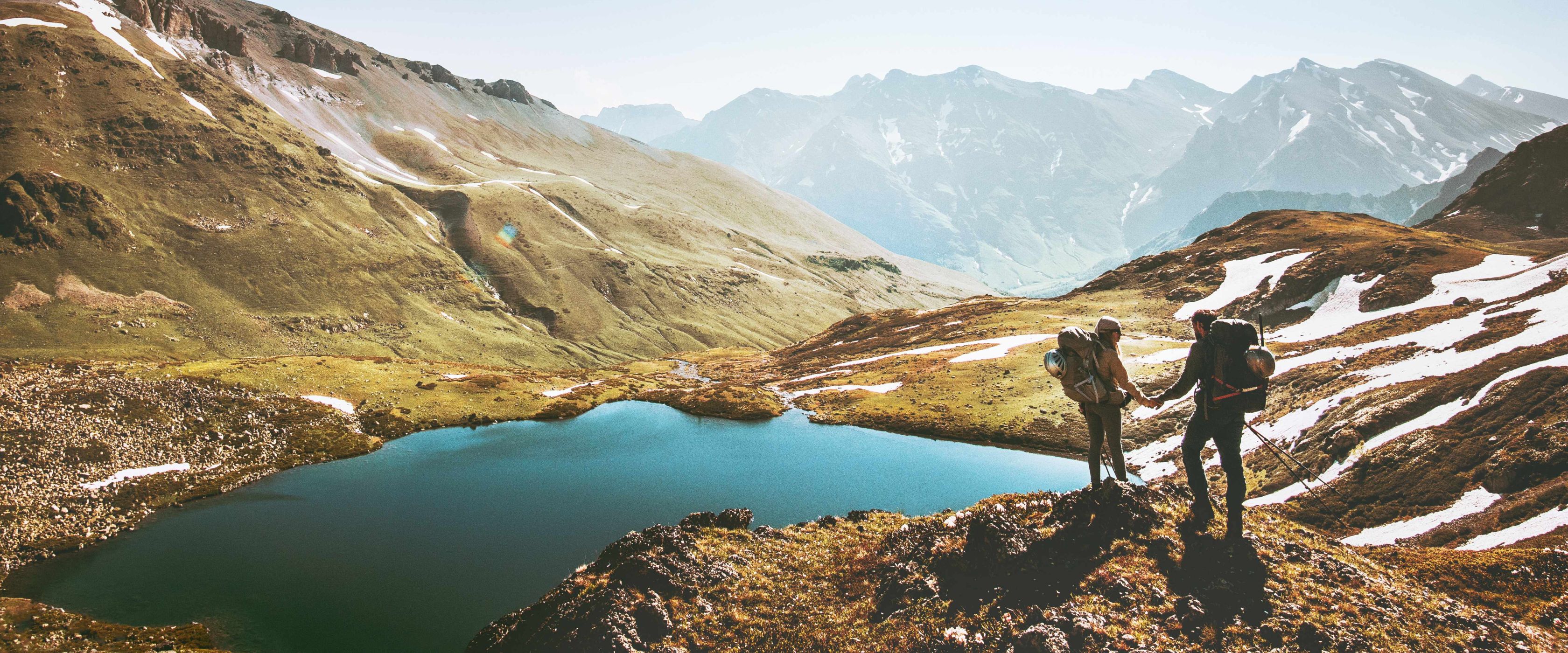 2 people hiking in the mountains near a lake