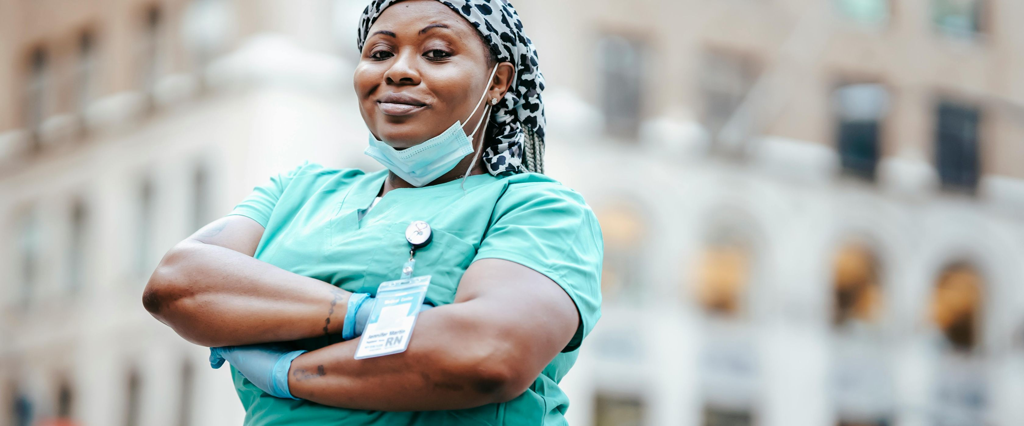 Black nurse standing proudly in scrubs and badge
