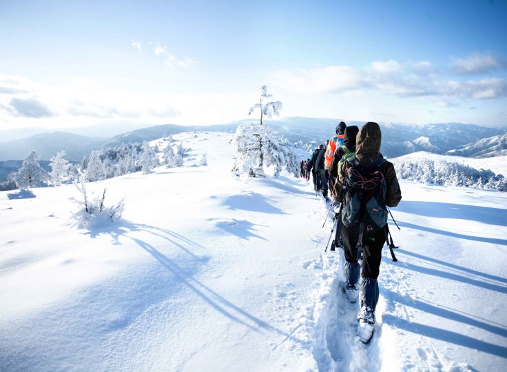 People show shoeing through snowy hills