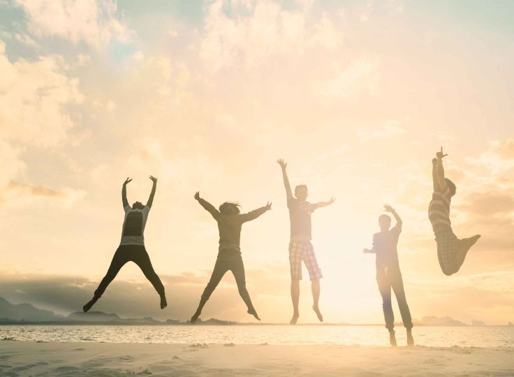 People jumping into the air with a sunset in the background