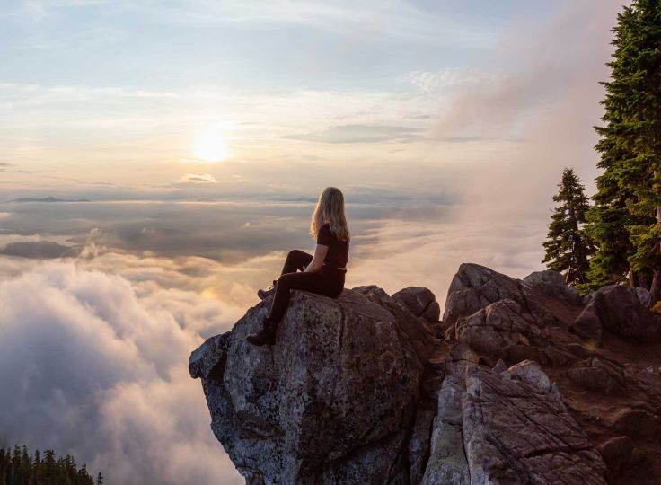 Women sitting on a cliff overlooking a valley