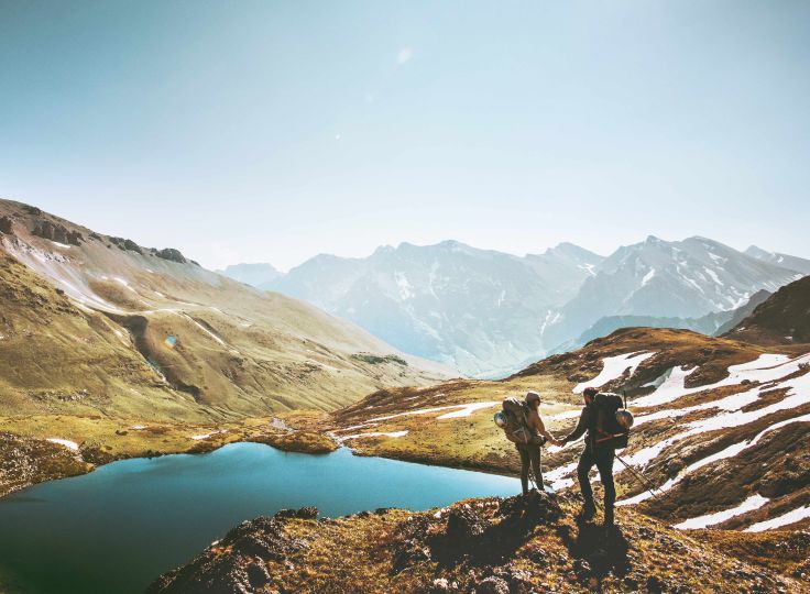 2 people hiking in the mountains near a lake